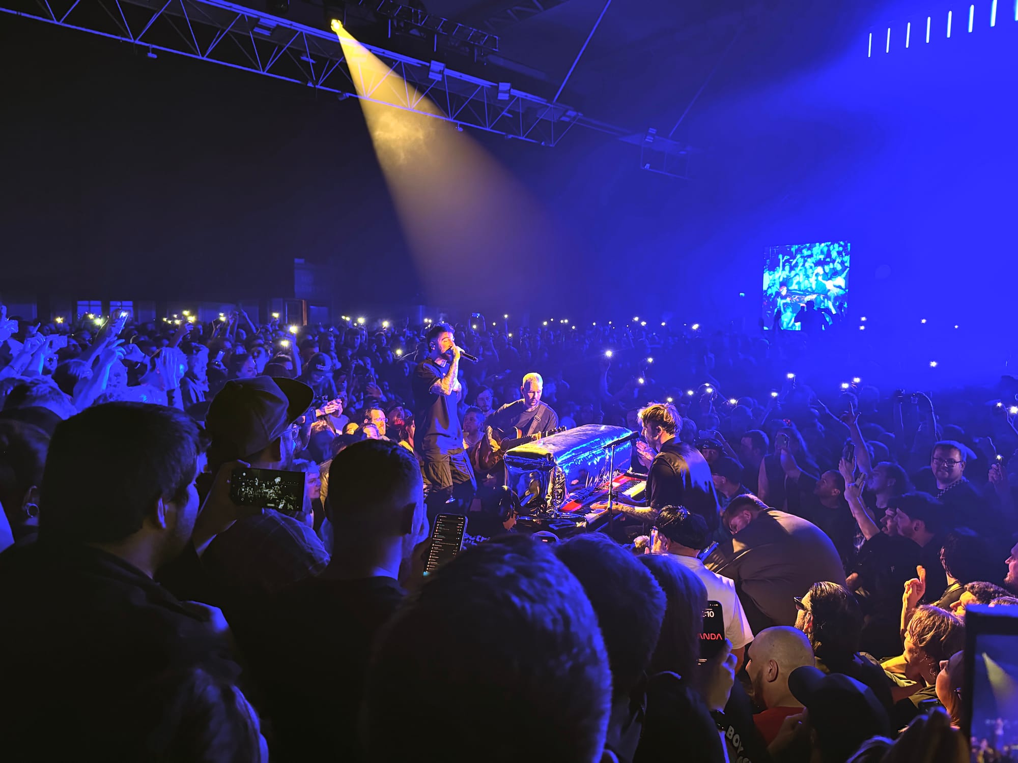 Nico, Danskimo, and Kevin in the middle of the crowd with a piano and acoustic guitar. wide shot